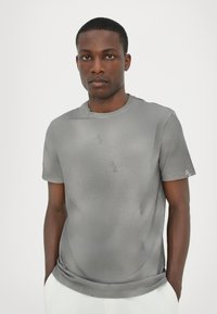 Grijze korte mouwen T-shirt met een ronde hals, met subtiele logopatronen en een gladde, zachte textuur. Schoon ontwerp met minimale details.