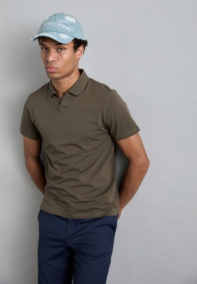 Olívovo zelené polo tričko s klasickým golierom, skombinované s námorníckymi modrými nohavicami a svetlomodrou čiapkou so vyšitým textom.