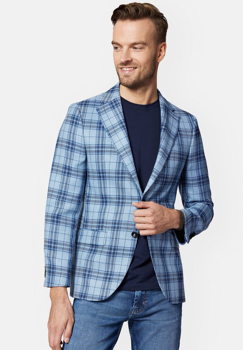 Jasnoniebieska marynarka w kratę z materiału z granatowymi akcentami. Posiada zapięcie na dwa guziki, klapy w kształcie notcha i kieszenie boczne. Noszona na ciemnej koszuli.