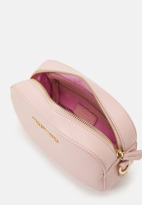 Pink leather bag with a rounded shape, gold zipper, and hardware; interior features a contrasting pink lining. Brand name embossed on front.