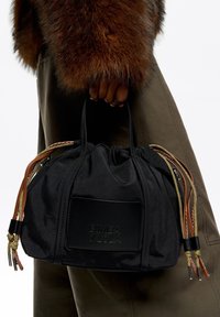 Bolsa de tela negra con parte superior recogida, con asas trenzadas en marrón y dorado, logo en relieve y superficie texturizada.