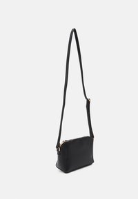 Borsa a tracolla in pelle nera con una forma strutturata, tracolla lunga e hardware con cerniera dorata, caratterizzata da una texture liscia e un design minimalista.