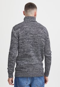 Gestrickter Rollkragenpullover in Grau- und Schwarztönen, mit strukturierten Mustern, gerippten Bündchen und einer taillierten Silhouette.