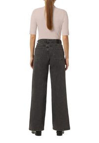 Schwarzweite Jeans mit weitem Bein und hohem Bund, ausgestattet mit zwei Gesäßtaschen und einem Etikett am Bund. Der Stoff hat eine weiche, strukturierte Oberfläche.