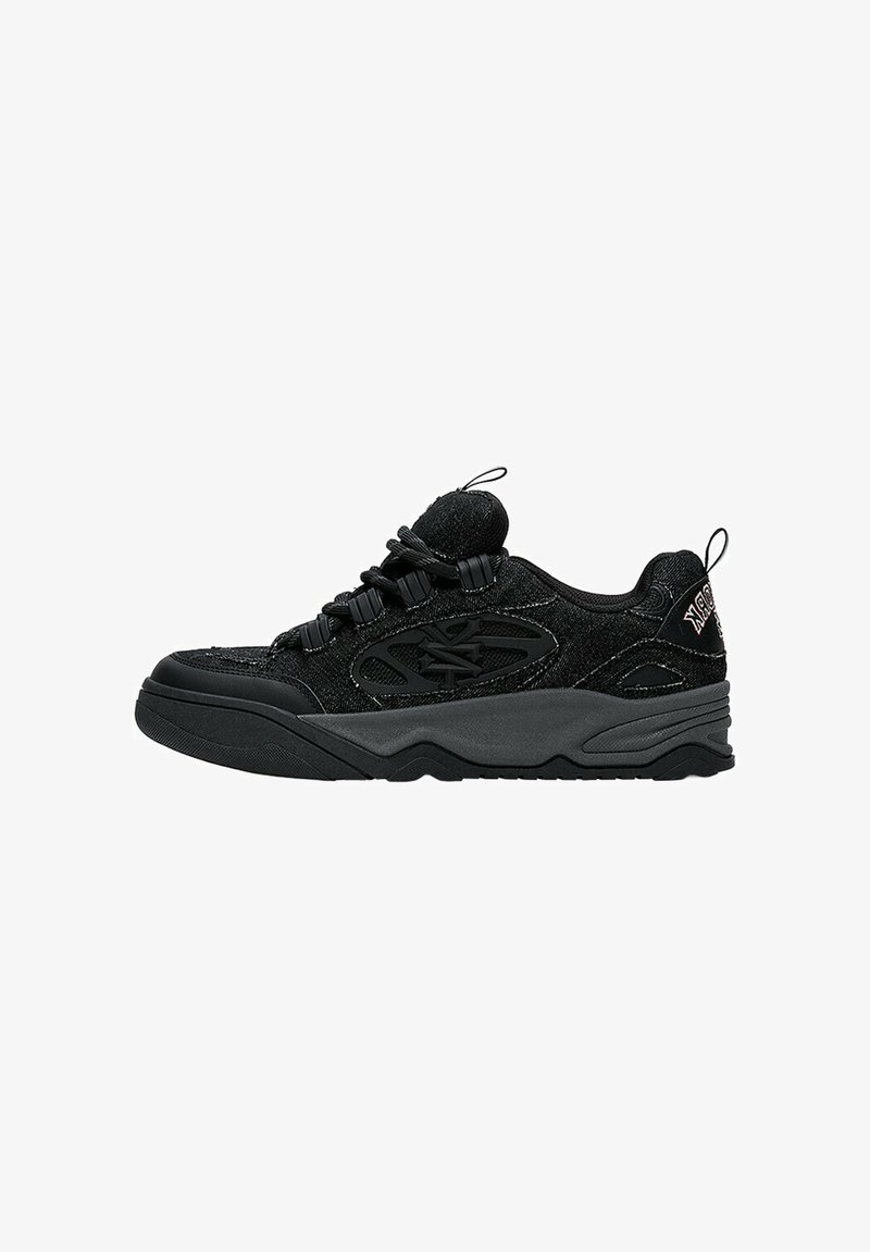 Baskets basses noires en tissu texturé avec semelle en caoutchouc, dotées de languettes à boucle et de lacets noirs avec œillets en plastique.