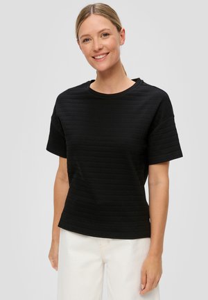 Czarna t-shirt z teksturą, z krótkimi rękawami i okrągłym dekoltem, z delikatnymi poziomymi paskami. W zestawie z jasnymi spodniami.