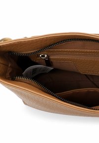 Interiér kožené kabelky svetle hnědé barvy s hladkou texturou, kapsou se zipem a organizéry. Akcenty zahrnují lemování zipu v černé barvě.