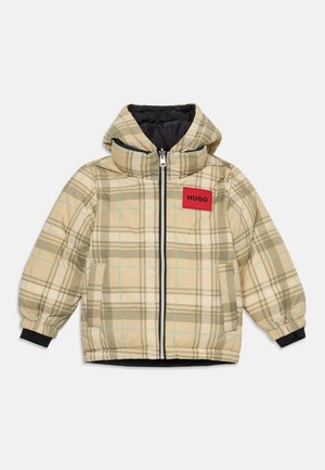 Bēša kvadrātu raksta pufīgā jaka ar kapuci, priekšējo rāvējslēdzēju, sānu kabatām, melnu iekšējo oderi un sarkanu uzlīmi ar uzrakstu "HUGO" uz krūtīm.