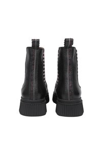 Czarne skórzane botki za kostkę z paskami po bokach, elastycznymi wstawkami i żebrowanymi gumowymi podeszwami. Zawierają kontrastowe detale w szwach.