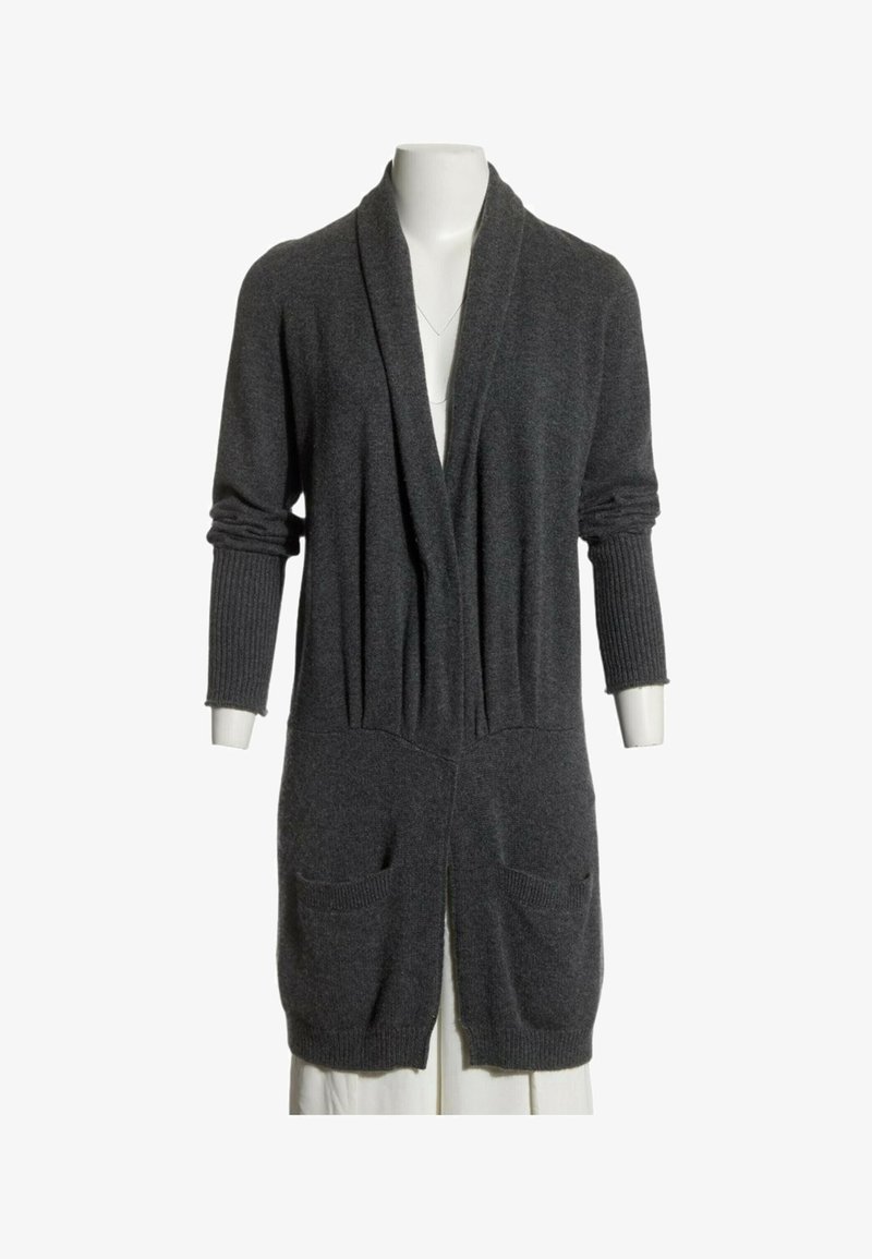 Cardigan long gris foncé avec col châle, manches longues côtelées, deux poches avant, présenté sur un mannequin avec un pantalon blanc.