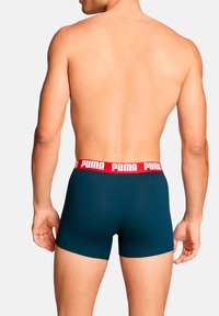 Boxershorts in dunklem Petrol mit einem roten Bund, der weißen Schriftzug "PUMA" zeigt. Das Material wirkt dehnbar und eng anliegend für Komfort.