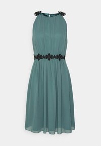 En turkos ärmlös klänning i lättviktsmaterial, med en plisserad design och svarta blommiga broderade detaljer vid halsringningen och midjan.