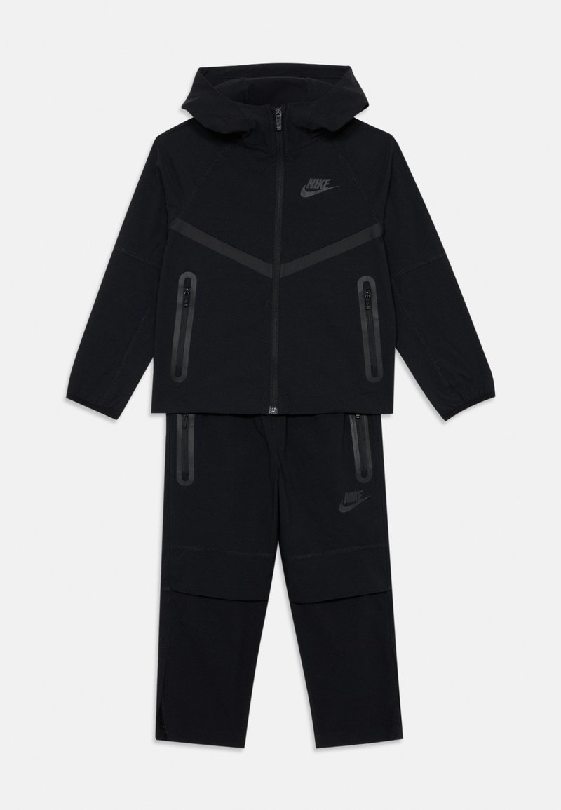 Trening Nike negru format dintr-o hanorac cu fermoar, cu un design căptușit, și pantaloni cu buzunare cu fermoar. Material moale cu o finisare matt.