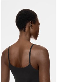 Zwarte top met verstelbare dunne bandjes, een gladde textuur en een aansluitend ontwerp, van achteren gezien, waarin de contouren van de schouders en nek worden getoond.