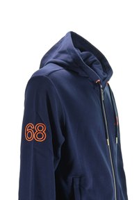 Felpa con zip di colore blu navy, con cappuccio, numero arancione "68" sulla manica destra e tasche frontali, esposta su uno sfondo bianco.