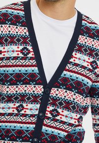 Navy cardigan with colorful geometric patterns in red, white, and blue. Features a V-neck, button closures, and a knitted texture.