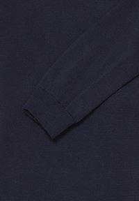 Pull à manches longues tricoté bleu marine foncé avec poignets côtelés, montré en gros plan sur une surface plane.