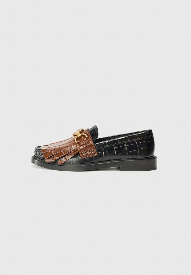 Black leather loafers feature a brown crocodile-textured strap with tassels and a gold buckle, displayed against a white background.