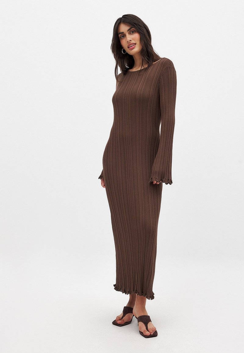 Robe en tricot côtelé marron avec des manches longues et un ourlet festonné, fabriquée en matériau extensible, au design ajusté qui atteint les chevilles.