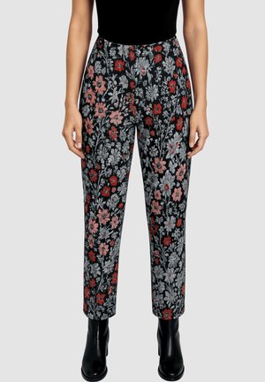 Pantalones con estampado floral en negro que presentan flores rojas y grises. Corte recto, con una cinturilla cómoda y bolsillos laterales. Combinados con botas negras.
