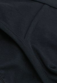 Mörk marinblå bomullstyg med en mjuk textur, med platta sömmar och en jämn finish, vilket framhäver dess töjbara och lätta design.