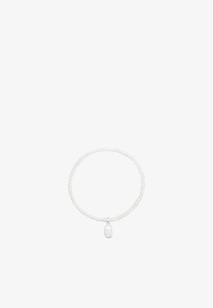Bracelet composé de petites perles blanches avec un petit pendentif ovale argenté orné d'un motif d'étoile découpée suspendu au centre.