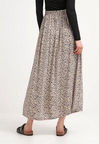 Floral maxi rok van lichte stof met een elastische taille. Heeft een crèmekleurige achtergrond en kleine bloemenpatronen in blauw, paars en roze.