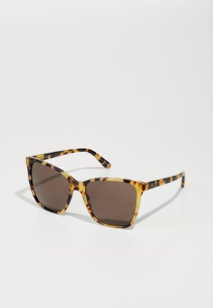 Ochelari de soare cu un cadru de tortoise, în formă pătrată, cu lentile brune cu gradient și un accent de aur pe braț. Cadru din plastic texturat cu modele variate.