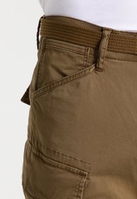 Bermuda marroni con cintura intrecciata, dotate di tasche laterali e una texture liscia. Il tessuto sembra resistente e leggero.