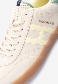 Beige ruskindsneaker med en gul læderstribe, cremefarvede snørebånd, gummisål og grøn detalje ved kraven. "HARPER AND NEYER" præget detalje.