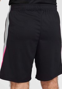 Pantaloni sportivi neri realizzati in un tessuto leggero e strutturato. Presentano strisce laterali grigie e rosa e una vita elastica per il massimo comfort.