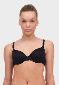Black bra with padded cups, lace trim detail, and scalloped straps. Smooth fabric with a seamless design and adjustable hooks at the back.
