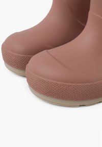 Stivali in gomma impermeabili marroni con suola antiscivolo testurizzata e parte superiore liscia, caratterizzati da una punta rotonda e un design minimalista.