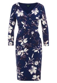 Marinblå blommig klänning med långa ärmar, V-ringning och rynkad detalj vid midjan. Har vita och ljuslila blommor på en texturerad tyg.