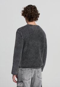 Maglione grigio a coste con scollo rotondo e maniche lunghe, caratterizzato da un motivo testurizzato. La parte posteriore è liscia e presenta una vestibilità comoda.