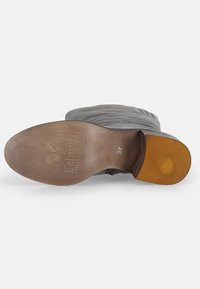 Bottines en cuir gris avec un bout arrondi, présentant une semelle texturée marron clair. La partie inférieure comporte un logo et une empreinte de taille "37".