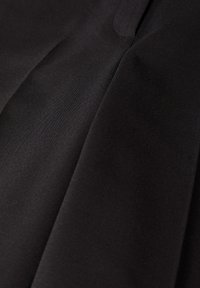 Tissu noir lisse avec des plis doux et un léger éclat, montrant la texture et la chute du matériau.