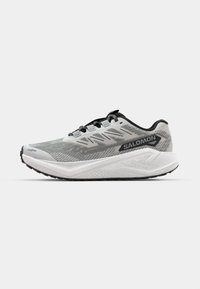 Chaussure de course grise avec une tige en maille, des accents noirs et une semelle intermédiaire blanche. Dispose d'un embout renforcé et de lacets plats pour un maintien sécurisé.