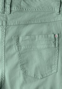 Minzgrüne Jeans mit einer Gesäßtasche, die horizontale Nähte und einen silbernen Metallakzent aufweist. Hergestellt aus weichem, leichtem Stoff.