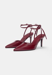 Burgundy läder högklackade sandaler med spetsiga tår, vristband och smala klackar. Slät textur med minimala design detaljer.