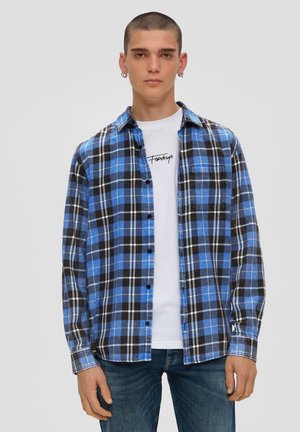 Blue and black plaid flannel shirt with long sleeves, button closure, and front pocket, layered over a white graphic t-shirt.