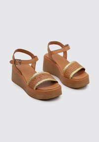 Brown wedge sandals with braided golden accents, adjustable ankle strap, and textured platform. Smooth leather upper and cushioned footbed.