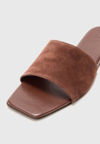 Brune semsket skinn slide sandal med en bred topprem og firkantet tå. Glatt lærsåle og flat såle. Ingen ytterligere pynt.