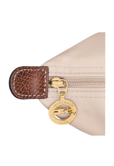 Beige Nylon-Tasche mit einem braunen Lederakzent, ausgestattet mit einem goldenen Reißverschluss und einem runden goldenen Anhänger mit der Inschrift "LONGCHAMP 1948".