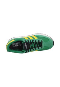 Sneaker verde Adidas con strisce gialle, lacci neri e suola ammortizzata, visto dall'alto su sfondo bianco.