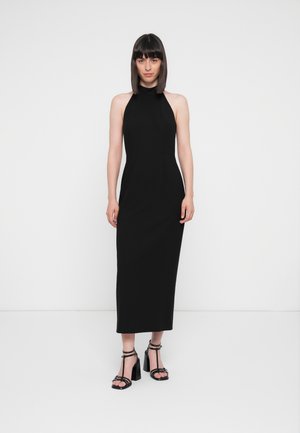 Svart halterneck maxikjole med en tettsittende silhuett, med en glatt tekstur. Brukt med strappy blokkhæl sandaler.