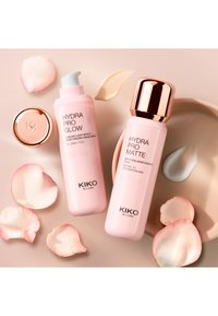 Cremas hidratantes Hydra Pro Glow y Hydra Pro Matte de KIKO Milano con muestras de crema y pétalos de rosa rosa sobre una superficie beige.