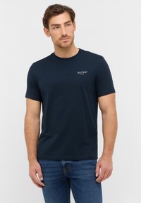 T-shirt bleu marine à manches courtes en coton, avec un col rond et un petit logo Mustang blanc sur la poitrine.