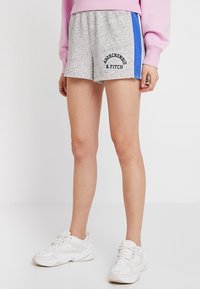 Grå sportshorts med blå sidostråk, med elastisk midja och texten "Abercrombie & Fitch" i svart.