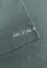 Donkergroene shirt met korte mouwen, met een zachte textuur en een lichtgrijs logo geborduurd op de mouw, met nette stiksels.